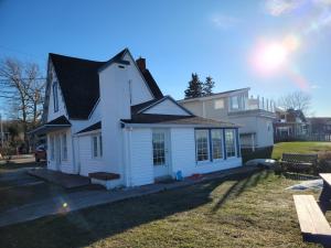 una casa blanca con techo negro en Maison du bord du fleuve à 5 min du centre ville en Rimouski