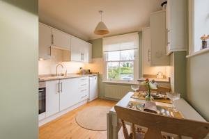 a kitchen with white cabinets and a table with chairs at Whitstable Hideaway by Bloom Stays in Whitstable