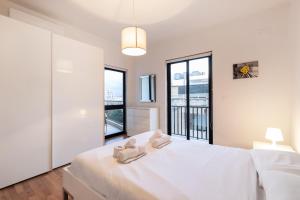 a white bedroom with a large bed with two towels on it at Spacious 3BR APT in Prime Location of St Julians by 360 Estates in Tal-Għoqod