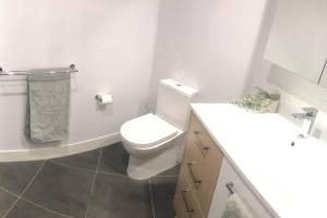 Baño blanco con aseo y lavamanos en Unit 2 - Manly Boutique Apartments en Brisbane
