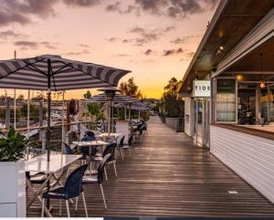a boardwalk with tables and umbrellas on a restaurant at Unit 2 - Manly Boutique Apartments in Brisbane