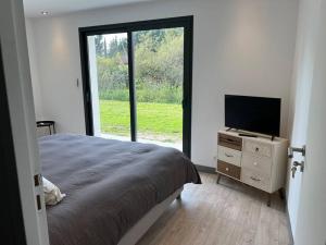 een slaapkamer met een bed en een televisie op een dressoir bij Grange Luxe rénovée plein centre in Arsac