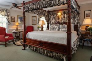 a bedroom with a canopy bed and a red chair at A Williamsburg White House Inn in Williamsburg