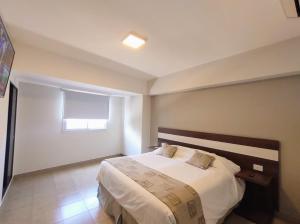 Urquiza Suites Salta في سالتا: غرفة نوم بسرير كبير مع شراشف بيضاء ونافذة