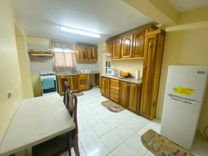 eine Küche mit Holzschränken, einem Tisch und einem Kühlschrank in der Unterkunft Russell Heights Vacation Home in Kingston