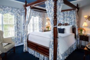 1 dormitorio con cama con dosel y cortinas azules en A Williamsburg White House Inn en Williamsburg