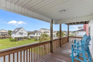 a blue chair sitting on a porch with a view of a house at Life of Sea-Renity 112 Burlington Street home in Holden Beach +28 photos