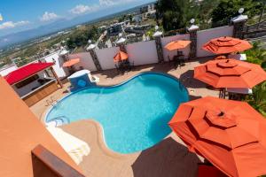 een uitzicht over een zwembad met parasols bij Vivy Hill's Hotel in Port-au-Prince