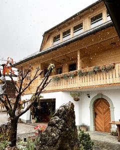 a snow covered building with a tree in front of it at Apartmaji Katrnjek in Bohinj