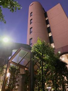 een hoog bakstenen gebouw met een boom ervoor bij Inuyama City Hotel in Inuyama