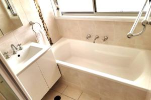 a bathroom with a white tub and a sink at Cheerful 3 bedrooms with free parking in Kingswood