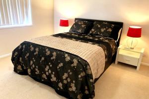 a bedroom with a black and white bed with two lamps at Cheerful 3 bedrooms with free parking in Kingswood