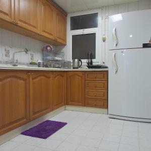 - une cuisine avec des placards en bois et un réfrigérateur dans l'établissement A Home Away From Home, à Abu Dhabi