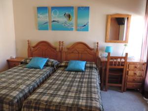 a bedroom with two beds and a table and a desk at Hostal Sali in Pelabravo