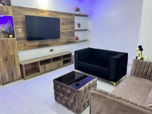 a living room with a black couch and a tv at Clique Court Hotel & Suite in Opete