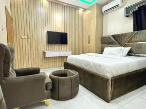 een slaapkamer met een bed en een stoel en een tv bij Clique Court Hotel & Suite in Opete