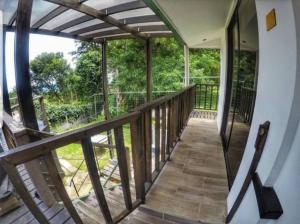 einen Holzbalkon mit Blick auf die Bäume in der Unterkunft Casa Vistas del Conde in Heredia