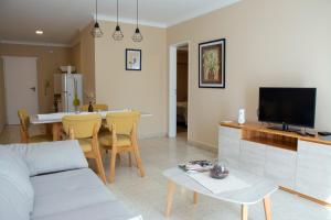 a living room with a couch and a table with a tv at Paseo Bolivar Hotel in Azul