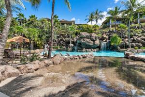 a swimming pool with a waterfall in a resort at Ho'olei Garden View by Coldwell Banker Island Vacation in Wailea