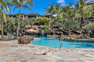 a resort pool with a waterfall and palm trees at Ho'olei Garden View by Coldwell Banker Island Vacation in Wailea