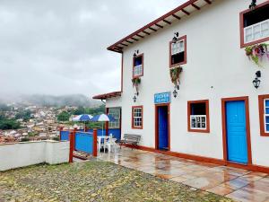a white building with blue doors and a table at Pousada Ouro Preto in Ouro Preto +90 photos