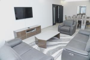 a living room with a couch and a tv and chairs at Appartment Luxe CAPUCINE dans la Zone B Dakar in Fass