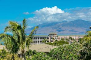 a hotel with palm trees and a mountain in the background at Ho'olei Ocean View by Coldwell Banker Island Vacations in Wailea
