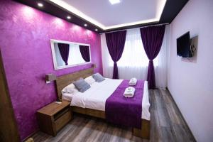 Dormitorio púrpura con cama y TV en Villa Panorama en Sarajevo