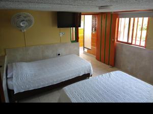 Un dormitorio con 2 camas y una puerta con ventilador. en Finca La Gaviota, en Montenegro
