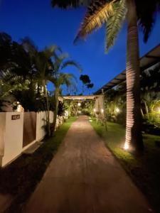 Una pasarela con sillas y palmeras por la noche. en La Reserve Design Villa IDA, en Pipa 74 fotos más