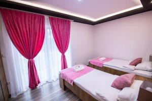 a room with two beds and a window with red curtains at Villa Panorama in Sarajevo