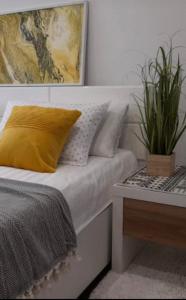 łóżko z żółtą poduszką i doniczką w obiekcie Apartman Jasmina w mieście Bihać