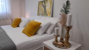 a bed with yellow and white pillows and candles on a table at Apartman Jasmina in Bihać