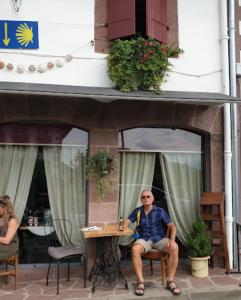 a man sitting at a table in front of a building at La vita e bella in Saint-Jean-Pied-de-Port
