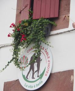 a sign on the side of a building with flowers at La vita e bella in Saint-Jean-Pied-de-Port
