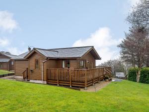 a log cabin with a deck and a yard at Ard Cuan in Torbeg