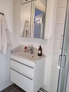 a white bathroom with a sink and a mirror at Archipelago villa, cabin & sauna jacuzzi with sea view, 30 minutes from Stockholm in Tyresö