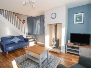 a living room with a blue couch and a tv at 6 Hunters Green Close in Chinley