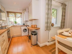 a kitchen with white cabinets and a wooden floor at 6 Hunters Green Close in Chinley