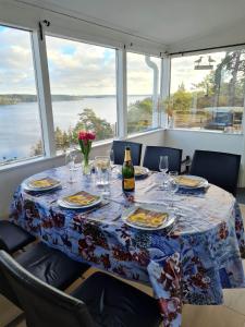 een tafel met borden en een fles wijn bij Archipelago villa, cabin & sauna jacuzzi with sea view, 30 minutes from Stockholm in Tyresö