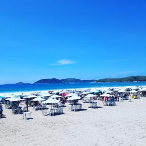 een groep parasols en stoelen op een strand bij Casas Chateau do Bom Baiano in Cabo Frio