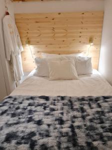 a bedroom with a large white bed with a wooden headboard at Archipelago villa, cabin & sauna jacuzzi with sea view, 30 minutes from Stockholm in Tyresö