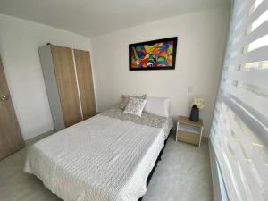 1 dormitorio con 1 cama y una pintura en la pared en Acogedor Apartamento Como en casa, en Manizales