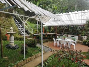 a white pergola with a table and chairs in a garden at Bosque de Niebla Birding & Nature in Cali
