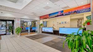 a store lobby with potted plants and large screens at Motel 6-Los Angeles, CA - Los Angeles - LAX in Inglewood +37 photos
