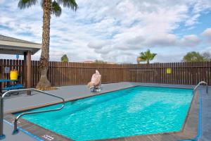 - une piscine avec une statue à côté d'une clôture dans l'établissement Motel 6-Eagle Pass, TX - Lakeside, à Eagle Pass