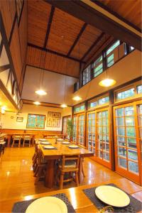 ein großes Esszimmer mit Holztischen und Fenstern in der Unterkunft Pension Ringo-no Ki in Hakuba