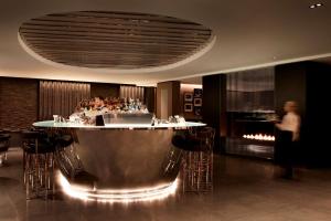 a bar in a restaurant with a person in the background at Hyatt Regency London Albert Embankment in London