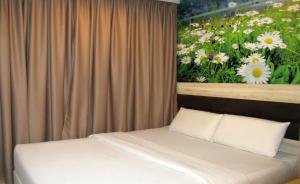 1 dormitorio con 1 cama y una pintura de flores en T-Hotel Bukit Bintang, en Kuala Lumpur