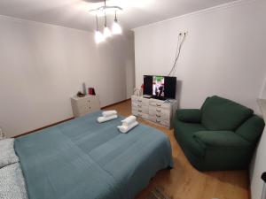 a bedroom with a bed and a couch and a tv at Segredos da Montanha by RetiroDoResende - Quarto Isolado in Seia